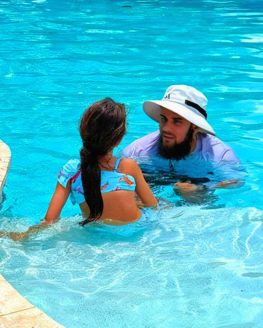 A TayyebiSwims instructor working with a young swimmer in the shallow end of a Houston backyard pool